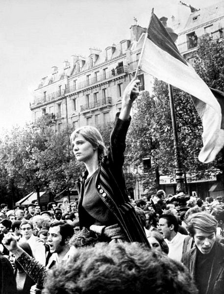 Manifestazione femminista con donna sulle spalle di un uomo che agita una bandiera.