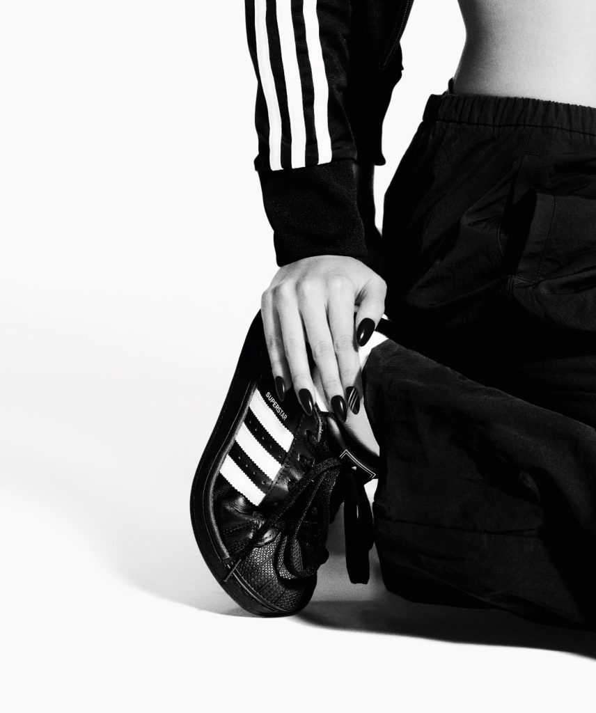 La cantante Jennie della banda di k-pop BlackPink. La foto mostra la sneaker Superstar del brand adidas in colore nero e le strisce bianche.