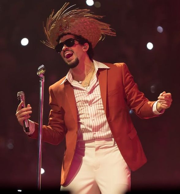 Concerto di Bad Bunny nei suoi Residency Shows in Porto Rico 2025. Indossa una giacca colore terracotta, camicia a righe, pantaloni bianchi e un cappello in paglia