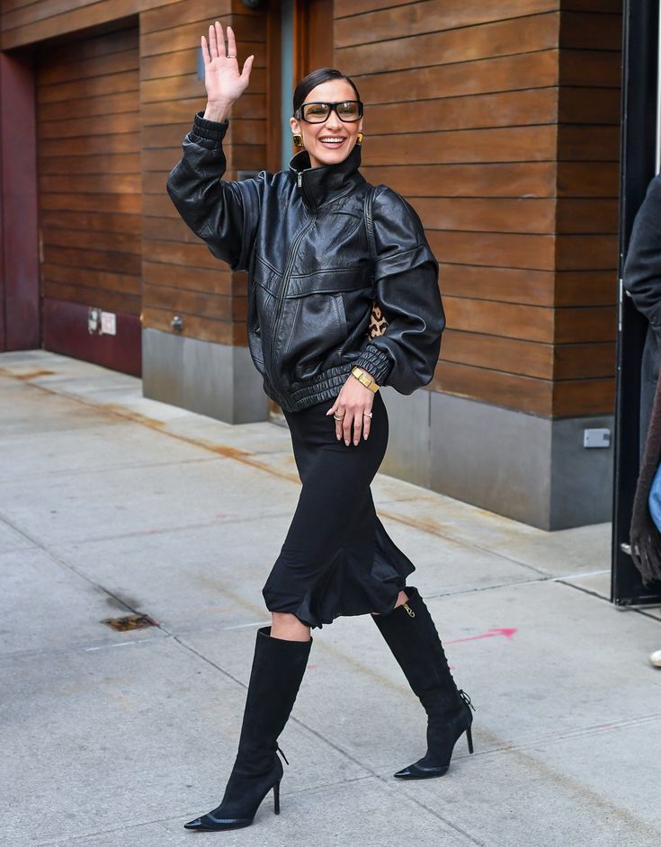 Look di Bella Hadid con occhiali da sole, giacca in pelle, gonna midi e stivali neri