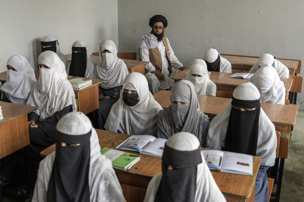 Bambine afghane che attendono scuola con il burka. Sono sedute normalmente e guardano avanti alla lezione
