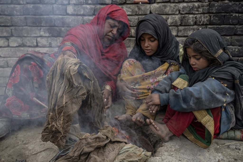 Foto di Ebrahim Noroozi per il premio di fotografia dell'anno 2024. Tre bambini che bruciano spazzatura, seduti a terra, per tenersi caldi