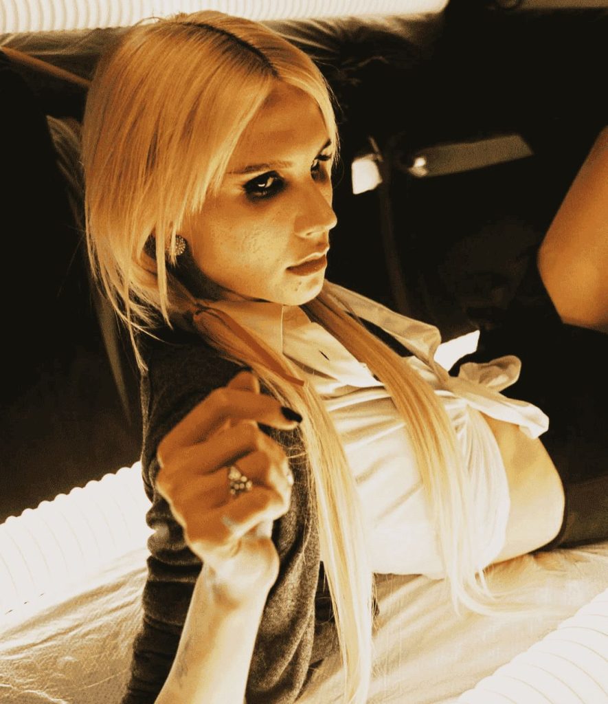 Ritratto contemporaneo con luce calda e trucco imperfetto che rappresenta l’estetica ugly beauty nella fotografia di moda.