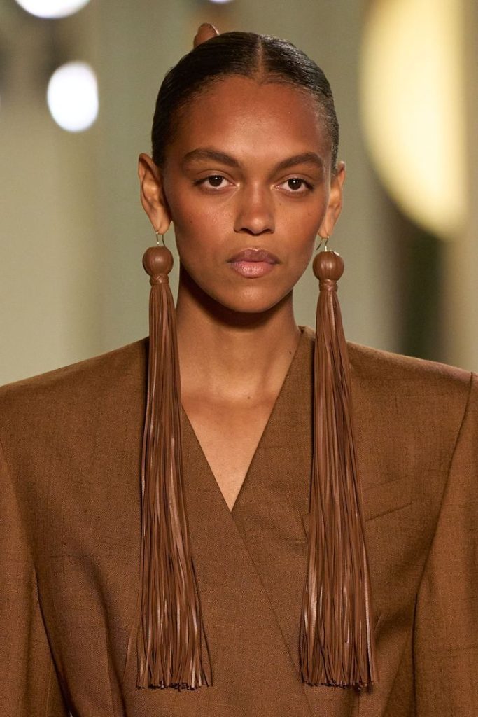 Orecchini lunghi fatti di nappine nella sfilata di Michael Kors. La foto si inserisce in un articolo hce parla delle tendenze dei gioielli del 2026