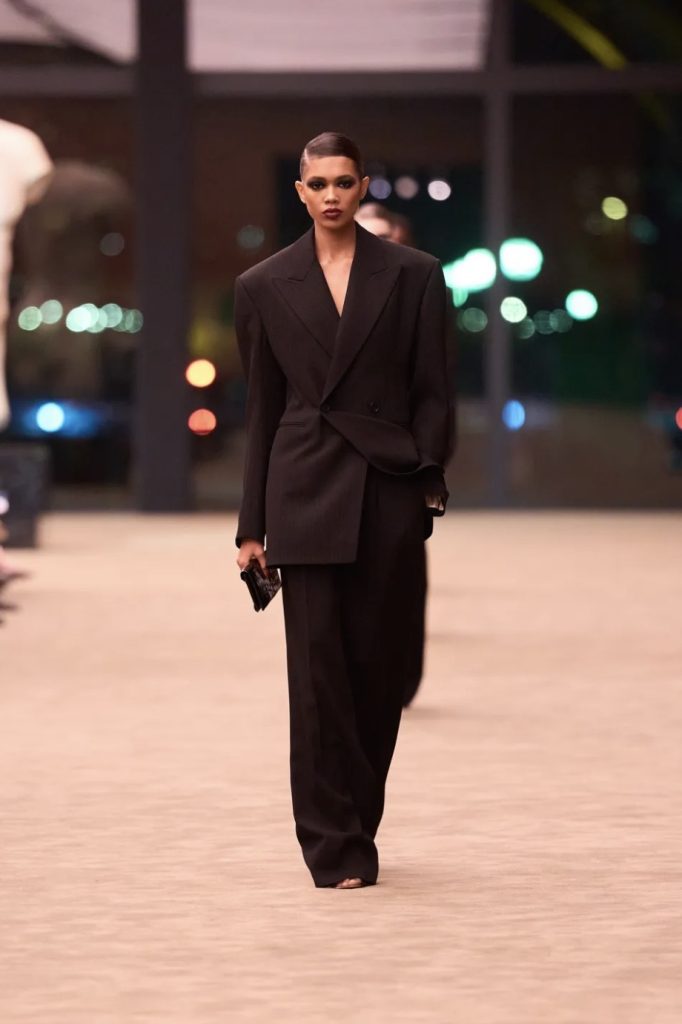 Saint Laurent propone un'eleganza più affilata. Giacche dalle spalle marcate, cappotti austeri e abiti in pizzo creano un equilibrio costante tra rigore e sensualità. 