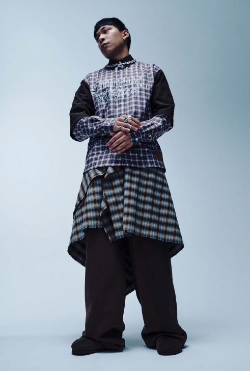Modello che indossa la collezione FW 2026-27 di GARCÍAS. Indossa un completo in tartan o madras con le maniche lunghe metà in colore nero e metà nella fantasia scozzese