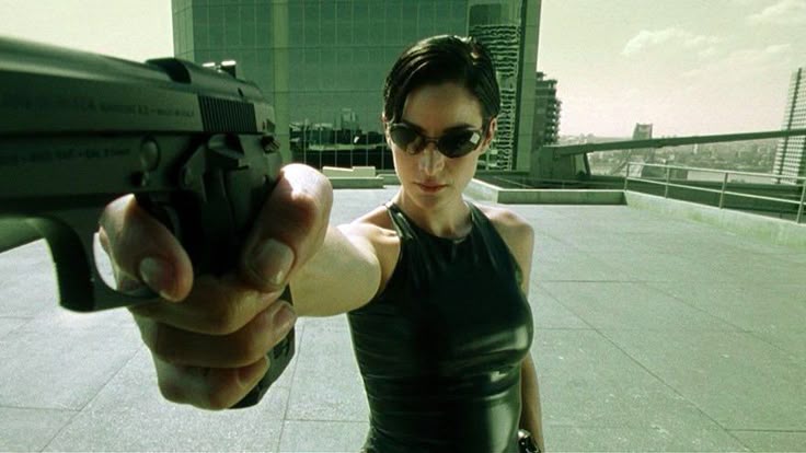 Trinity punta una pistola in una scena d’azione del film cyberpunk Matrix.
