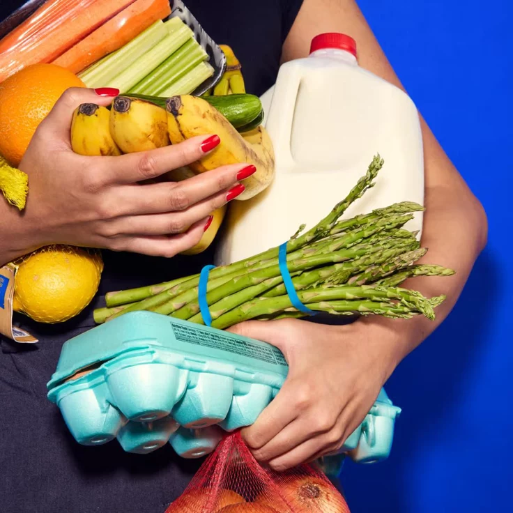 Immagine con sfondo blu e diversi alimenti tenuti in mano.