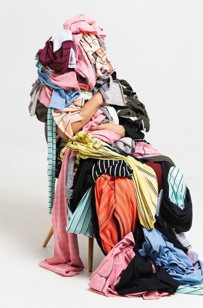 Immagine di una sedia con sopra ammassati diversi vestiti.