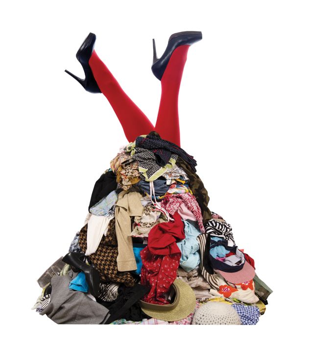 Immagine di gambe con scarpe nere col tacco e una pila di vestiti.