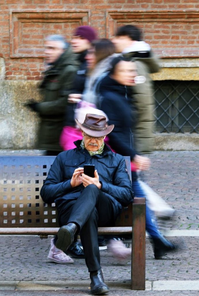 Immagine di un signore anziano al telefono seduto su una panchina.