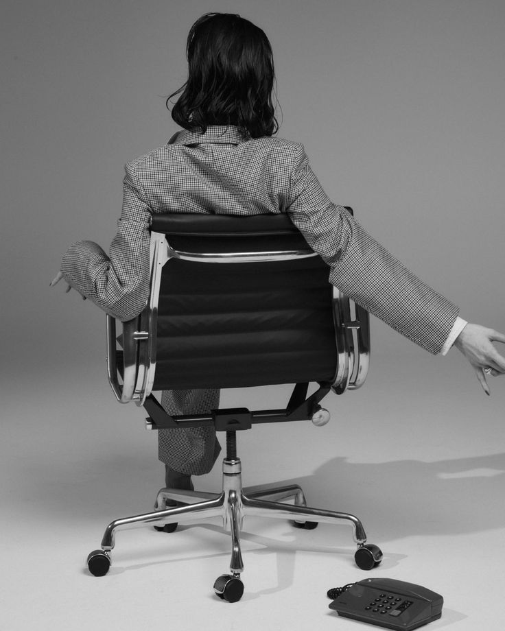 Immagine di una donna girata di spalle e seduta su una sedia.