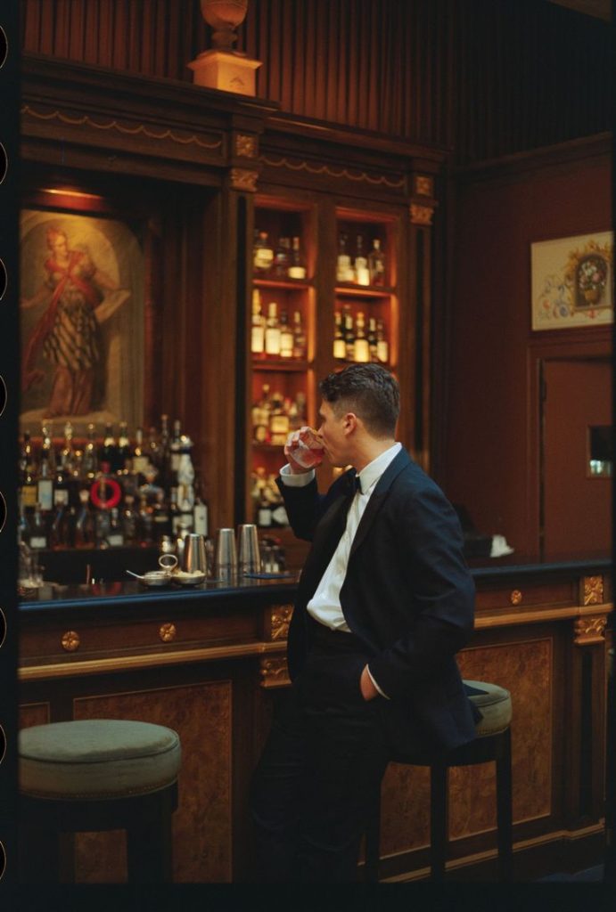 Persona che beve da un bicchiere al bar.
